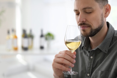 Man with glass of delicious wine indoors
