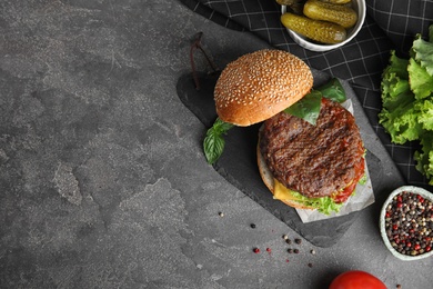 Delicious burger with meat cutlet on grey table, flat lay. Space for text