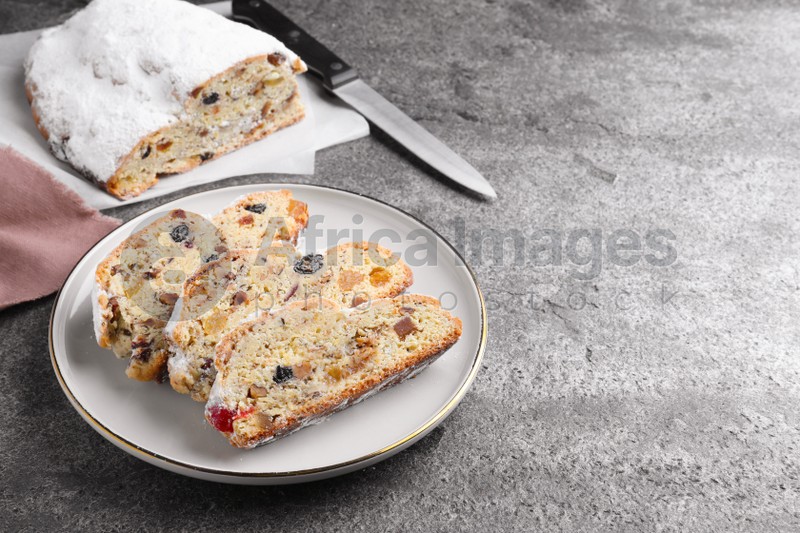 Traditional Christmas Stollen with icing sugar on grey table, space for text