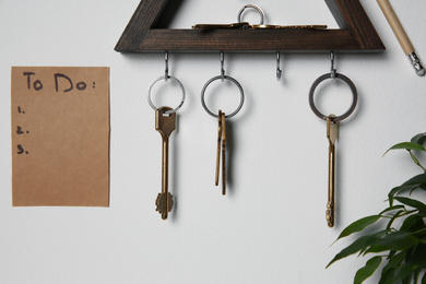 Wooden key holder and to do list on light grey wall indoors
