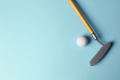 Golf ball and club on light blue background, flat lay. Space for text