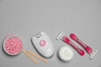 Modern epilator and other hair removal products on light grey background. Space for text