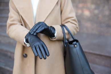 Woman with leather gloves and stylish bag on city street, closeup