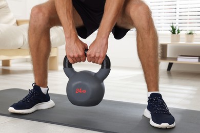 Man training with kettlebell at home, closeup
