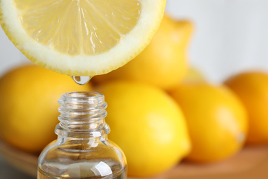 Citrus essential oil dripping from lemon slice into bottle, closeup. Space for text