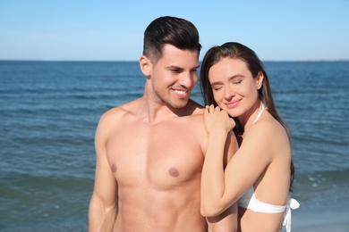 Woman in bikini and her boyfriend on beach. Happy couple