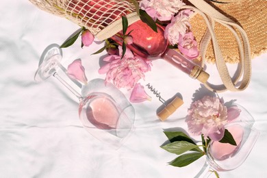 Flat lay composition with beautiful peonies and rose wine on white fabric