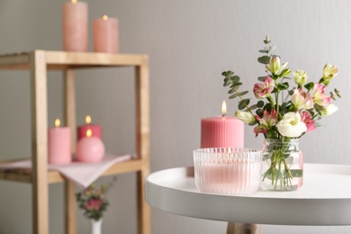 Stylish tender composition with burning candles and flowers on white table indoors, space for text. Cozy interior element