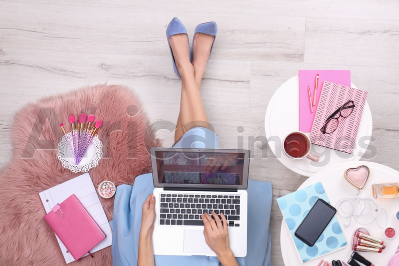 Photo of Beauty blogger with laptop and cosmetics sitting on floor, top view