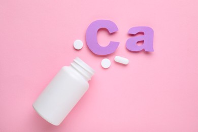 Pills, open bottle and calcium symbol made of purple letters on pink background, flat lay
