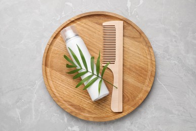 Dry shampoo spray, green twig and comb on light grey marble table, top view