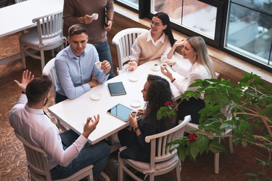 Group of coworkers having coffee break in cafe