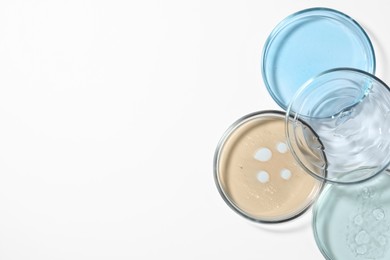 Photo of Petri dishes with color liquids on white background, flat lay. Space for text