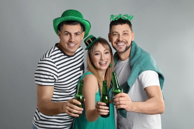 Happy people in St Patrick's Day outfits with beer on light grey background