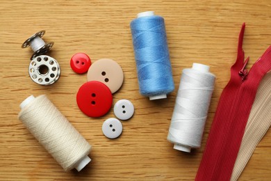 Photo of Flat lay composition with spools of threads and sewing tools on wooden table