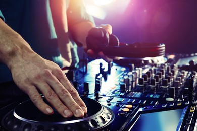 DJ creating music on modern console mixer in night club, closeup