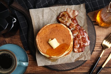 Delicious pancakes with maple syrup, butter and fried bacon on wooden table, flat lay