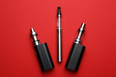 Electronic smoking devices on red background, flat lay