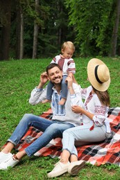 Happy family in Ukrainian national clothes on green grass outdoors