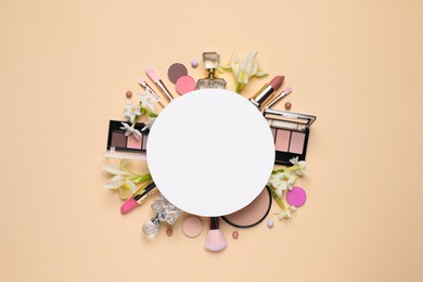 Photo of Flat lay composition with different makeup products, blank card and beautiful flowers on beige background, space for text