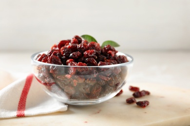 Dried cranberries in glass bowl on light table, closeup