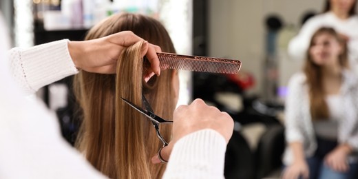 Hairdresser making stylish haircut with professional scissors in salon, closeup. Banner design