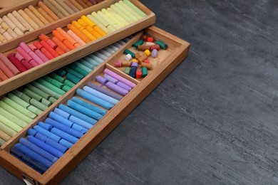 Colorful pastels in wooden trays on grey stone table, space for text. Drawing materials