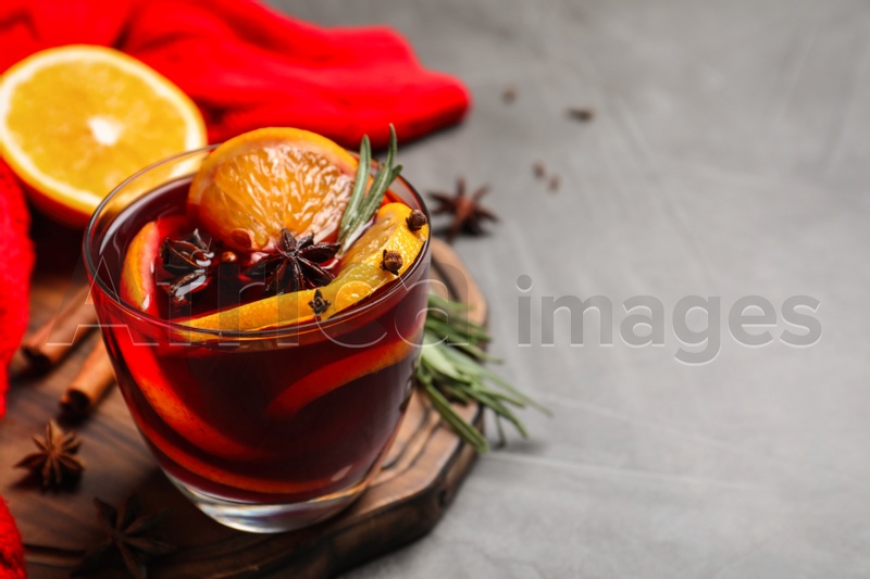 Glass with aromatic mulled wine on grey table. Space for text
