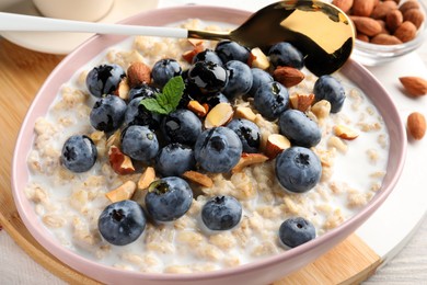 Photo of Tasty oatmeal porridge and ingredients served on table, closeup. Healthy meal