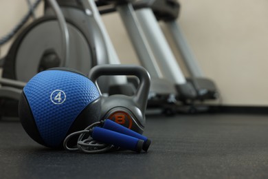 Photo of Blue medicine ball, kettlebell and skipping rope on floor in gym, space for text