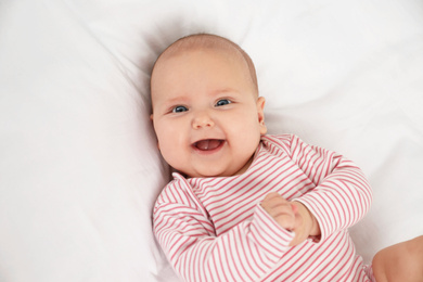 Cute little baby lying on white fabric, above view