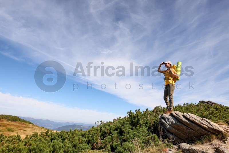 Young woman with backpack in mountains. Space for text