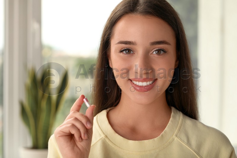 Young woman with dietary supplement pill at home