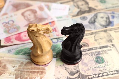 Wooden chess knights and different banknotes, closeup. Trade war concept
