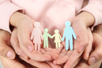 Parents and kid holding paper cutout of family in hands, closeup