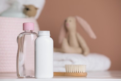 Photo of Bottles of baby cosmetic products and hair brush on white table. Space for text