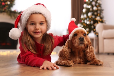Cute little girl with English Cocker Spaniel in room decorated for Christmas
