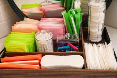 Wooden organizer with different feminine hygiene products on table, closeup