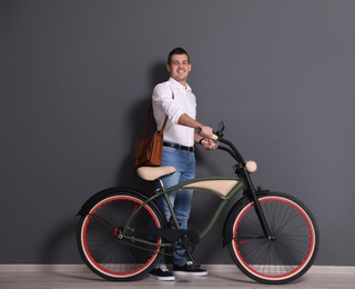 Portrait of handsome young man with bicycle near color wall