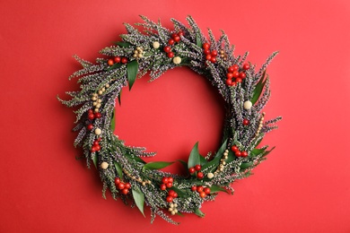 Beautiful heather wreath with berries on red background, top view. Autumnal flowers