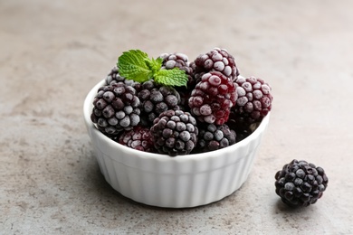 Tasty frozen blackberries with mint on grey table