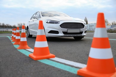 Modern car on test track with traffic cones, low angle view. Driving school