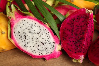 Different cut pitahaya fruits on wooden board, closeup