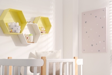 Hexagon shaped shelves on white wall in nursery. Interior design