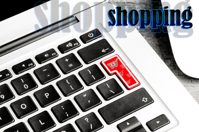 Closeup view of modern laptop keyboard with cart symbol on table. Internet shopping