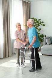Elderly woman and her husband with walking frame indoors