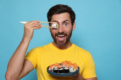 Photo of Emotional man hiding his eye with tasty sushi roll on light blue background