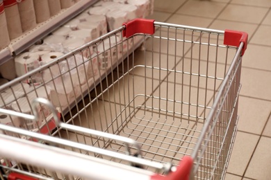 Empty metal shopping cart in supermarket, closeup