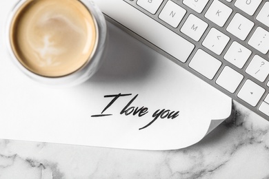 Card with text I Love You, cup of coffee and keyboard on white marble table, flat lay