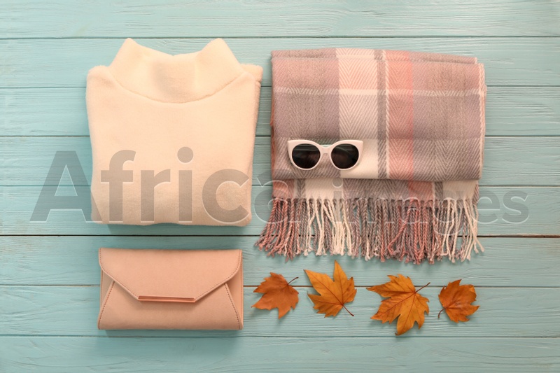 Photo of Flat lay composition with sweater and dry leaves on light blue wooden background. Autumn season